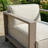 Outdoor lounge chair with beige cushions and matte metal armrest on patio