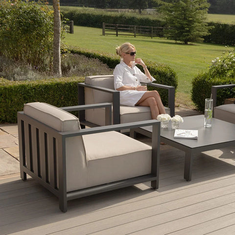 Grey outdoor lounge chair set with beige cushions and matching coffee table on patio decking