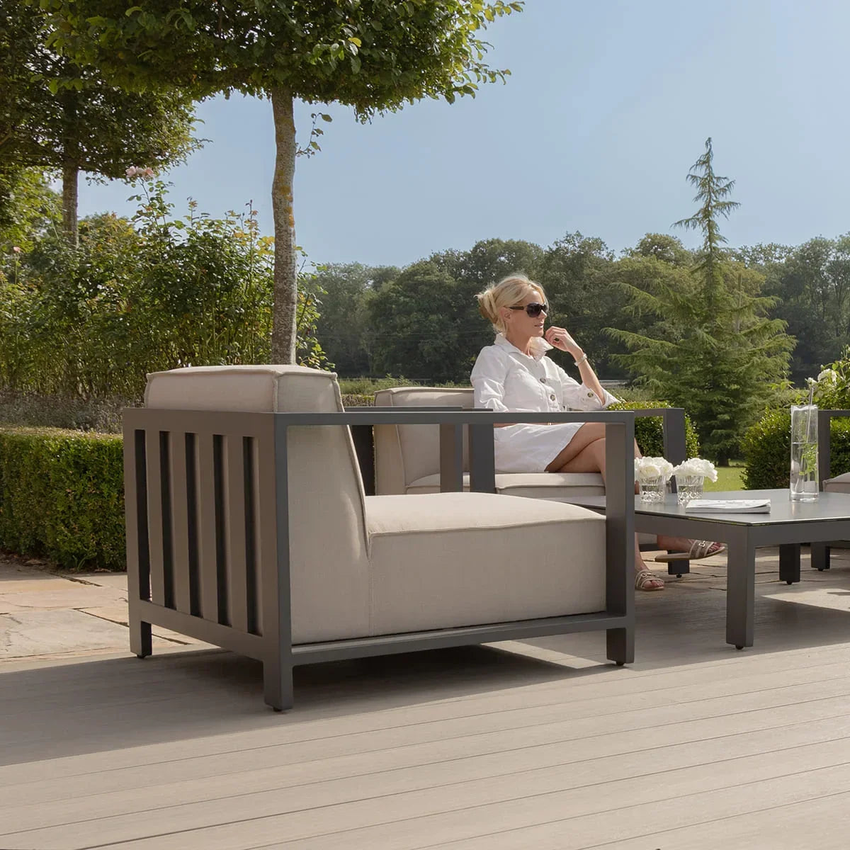 Grey metal frame outdoor armchair with beige cushions on patio beside coffee table