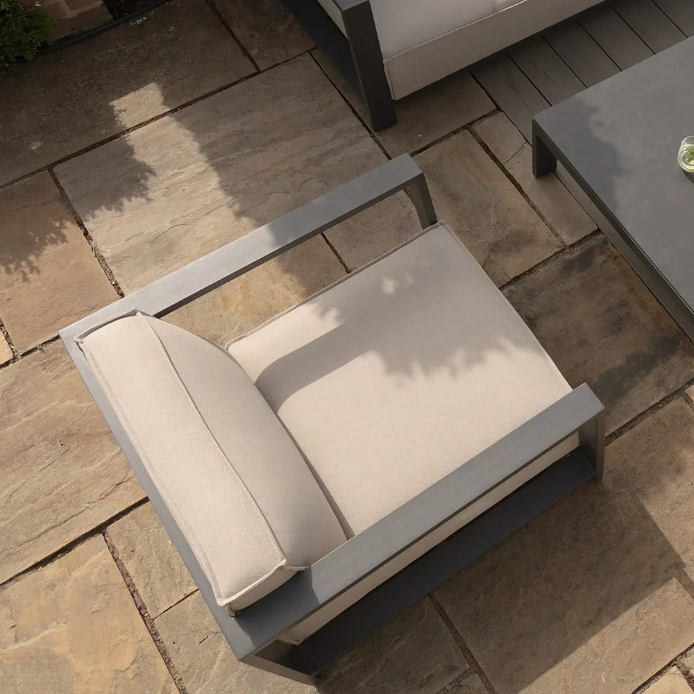 Beige outdoor armchair with metal frame on stone patio next to modern coffee table