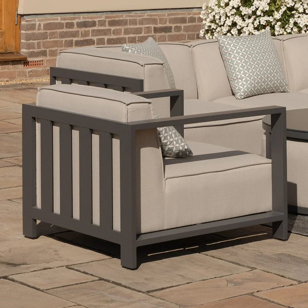 Modern outdoor armchair with grey aluminum frame and beige cushions on patio
