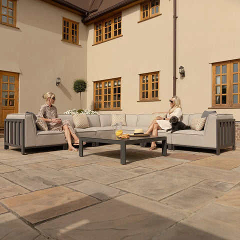 Grey outdoor corner sofa set with scatter cushions and coffee table on stone patio