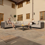 Grey outdoor corner sofa set with scatter cushions and coffee table on stone patio