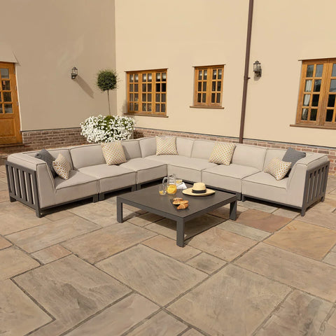 Grey outdoor corner sofa set with cushions and coffee table on patio
