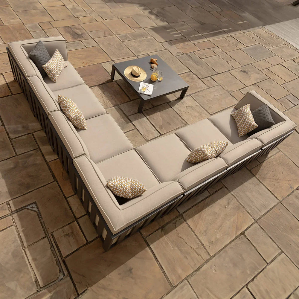 Beige corner outdoor sofa set with scatter cushions and coffee table on stone patio