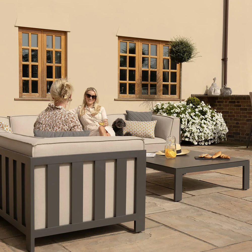 Grey outdoor sofa set with cream cushions and coffee table on stone patio