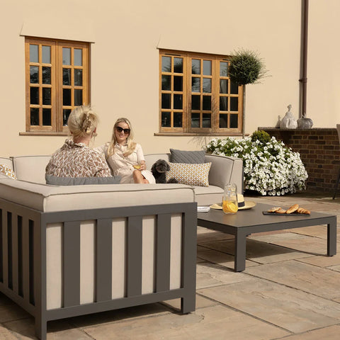Grey outdoor sofa set with cream cushions and coffee table on stone patio
