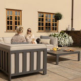 Grey outdoor sofa set with cream cushions and coffee table on stone patio