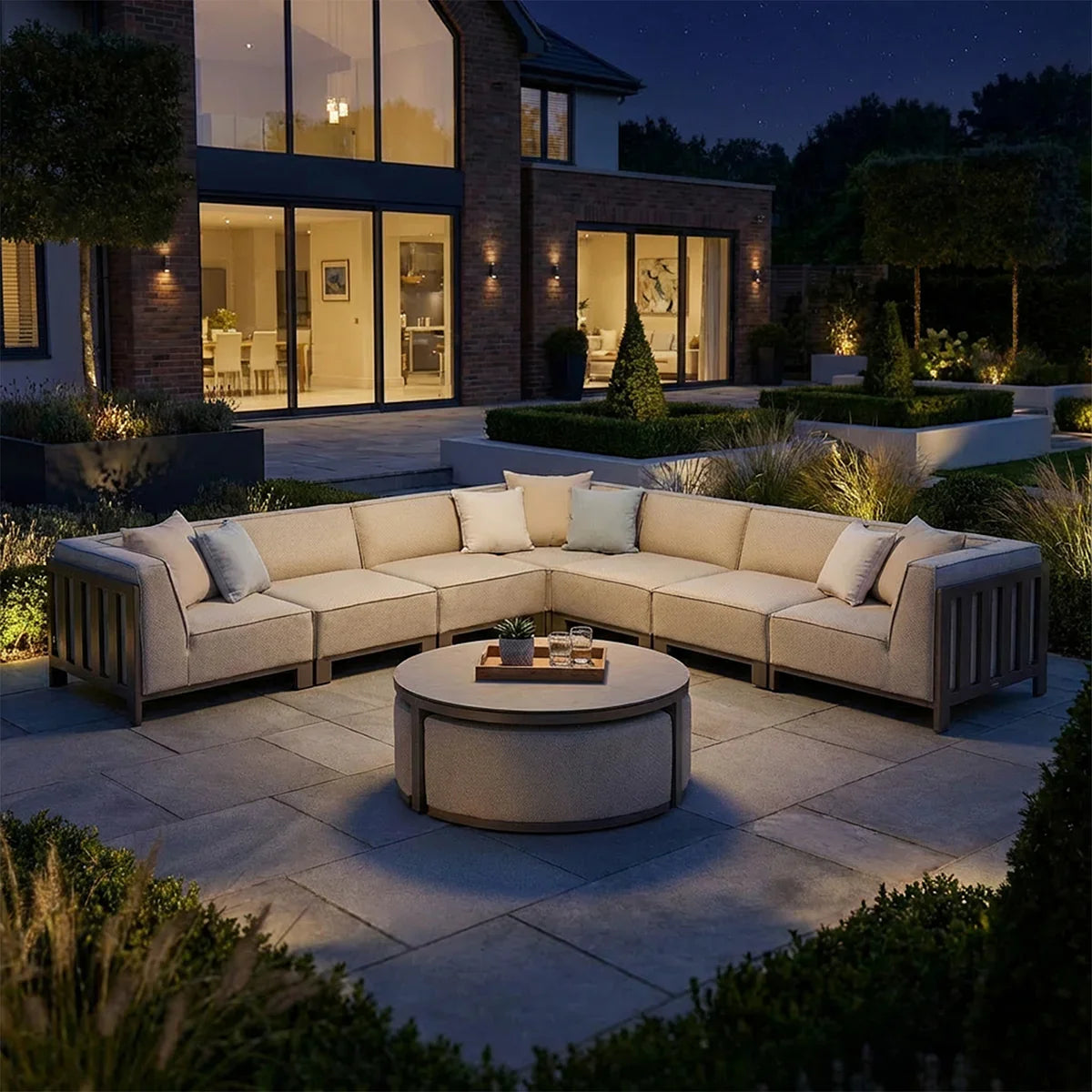 Outdoor corner sofa set with beige cushions and round coffee table on a modern patio at night