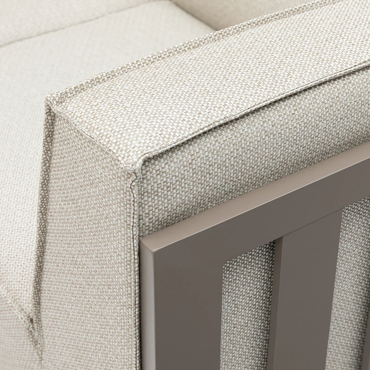 Close up of beige fabric sofa armrest with metal frame detail