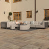 Grey outdoor corner sofa set with round coffee table and pouffes on stone patio