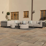 Light grey outdoor corner sofa set with coffee table and stools on stone patio