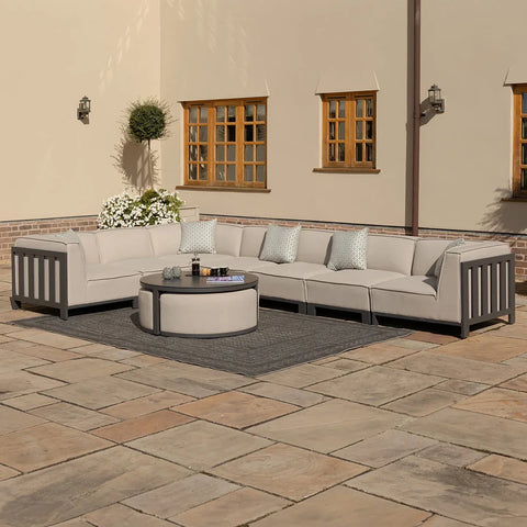 Beige outdoor corner sofa set with scatter cushions and round coffee table on patio