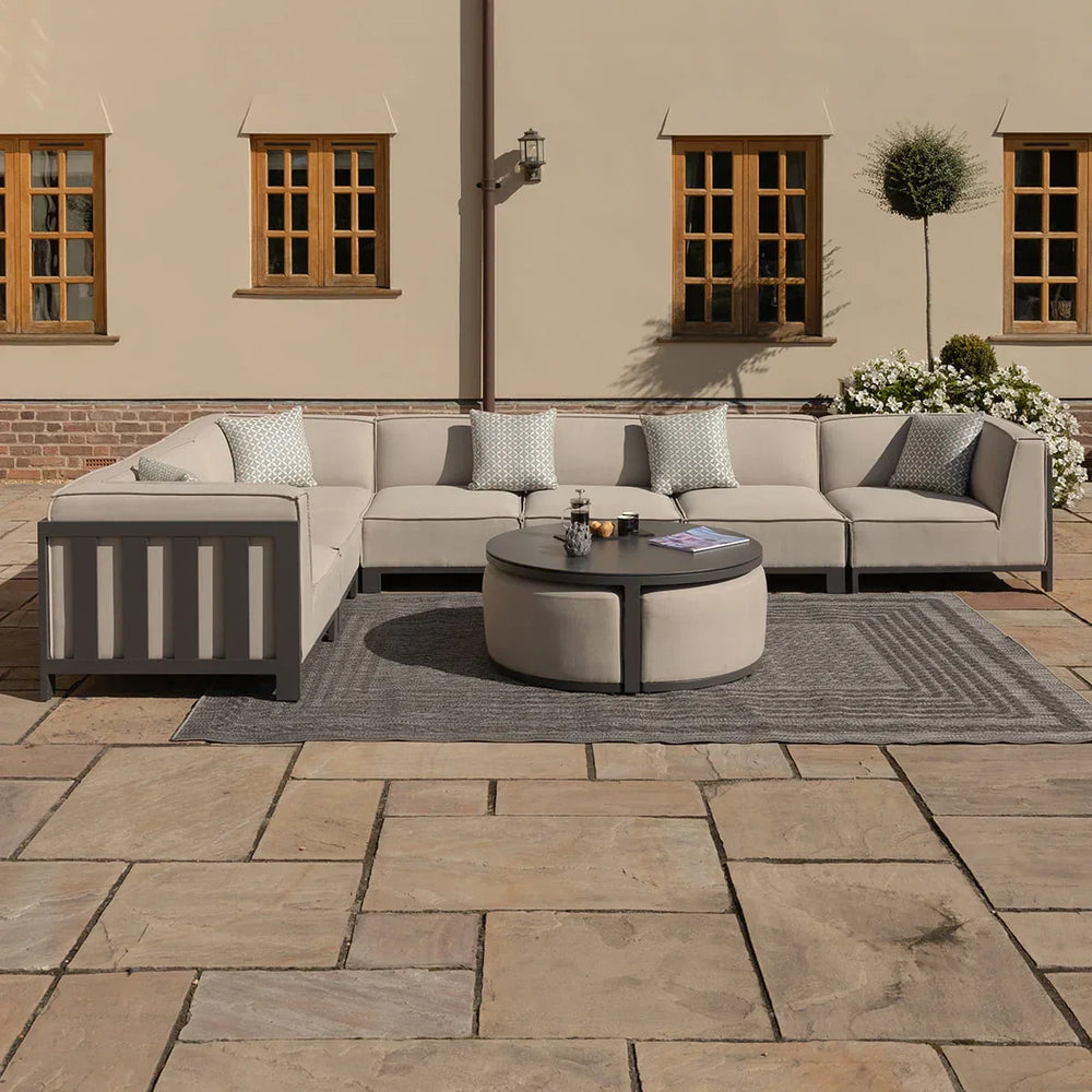 Beige outdoor corner sofa set with round coffee table and scatter cushions on a patio