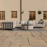 Outdoor corner sofa set with beige cushions, round coffee tables, and patterned pillows on patio