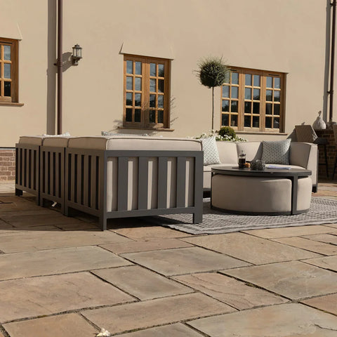 Grey outdoor sofa set with cushions and round coffee table on patio near house