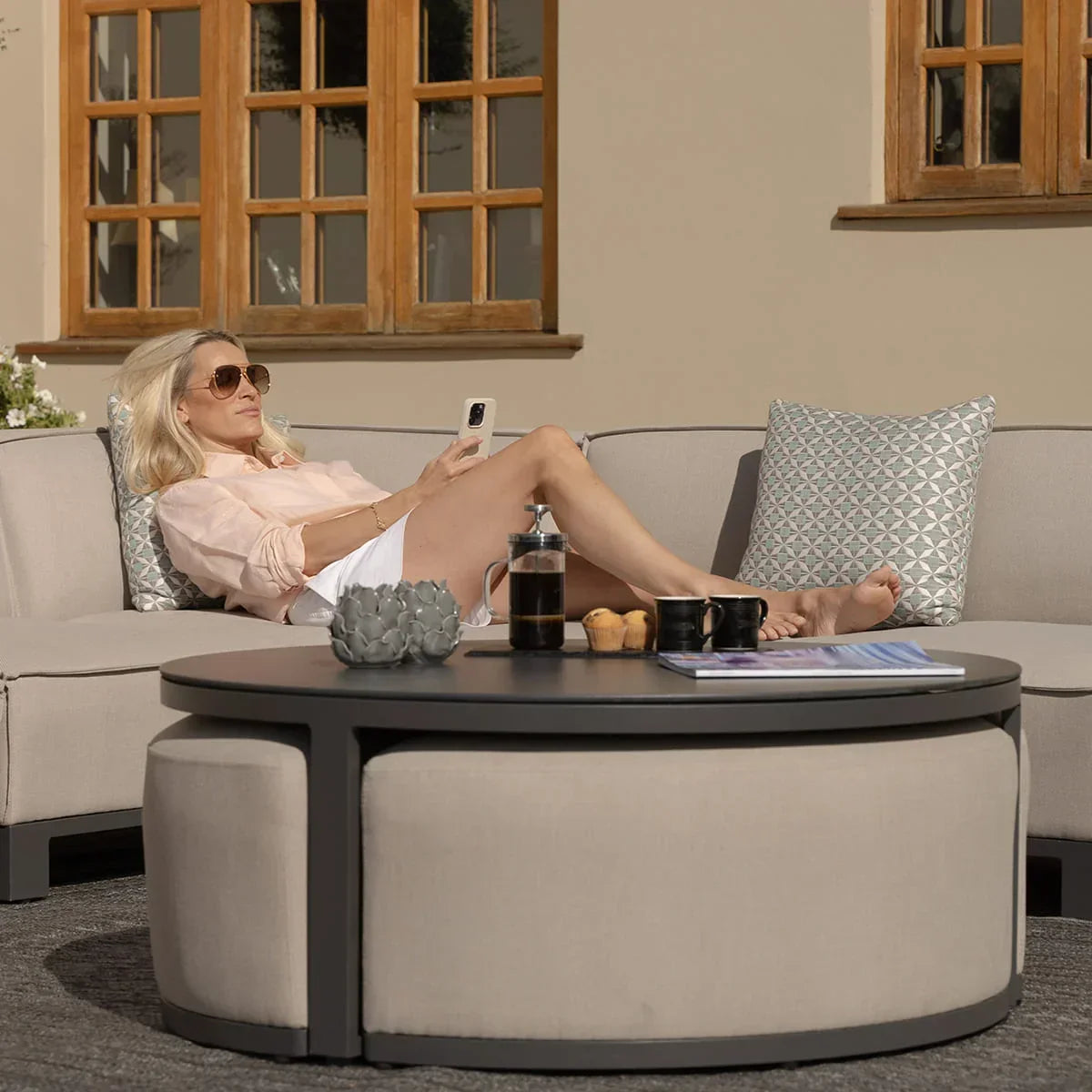 Outdoor corner sofa set with round coffee table and cushions on patio