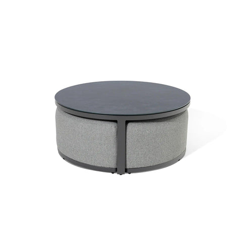 Round coffee table with black top and grey upholstered base on white background