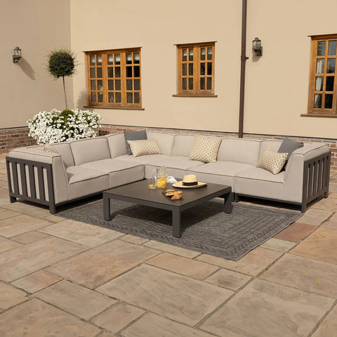 Grey outdoor corner sofa set with cushions and coffee table on stone patio