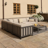 Grey outdoor corner sofa set with beige cushions and coffee table on stone patio