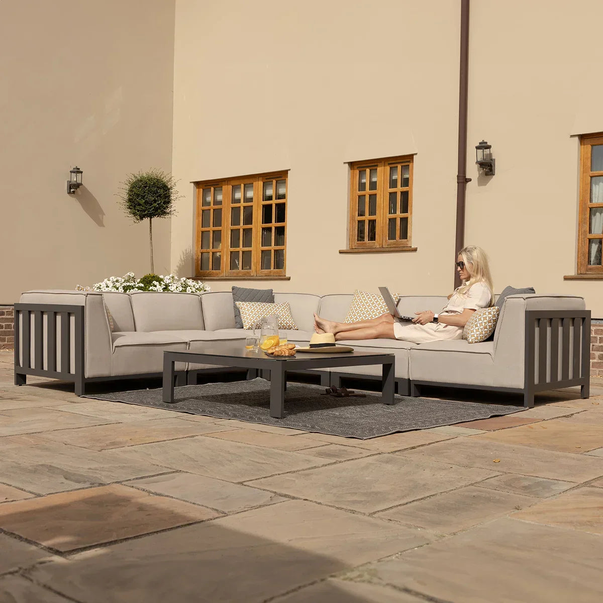 Grey outdoor corner sofa set with cushions and coffee table on stone patio