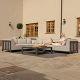 Grey outdoor corner sofa set with cushions and coffee table on stone patio