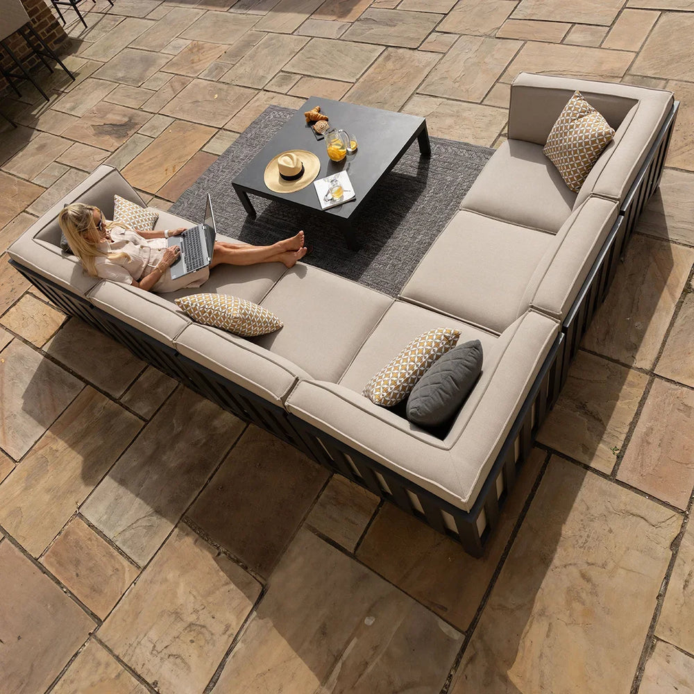 Beige outdoor corner sofa set with cushions and coffee table on a stone patio