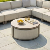Beige outdoor corner sofa set with round upholstered coffee table on stone patio