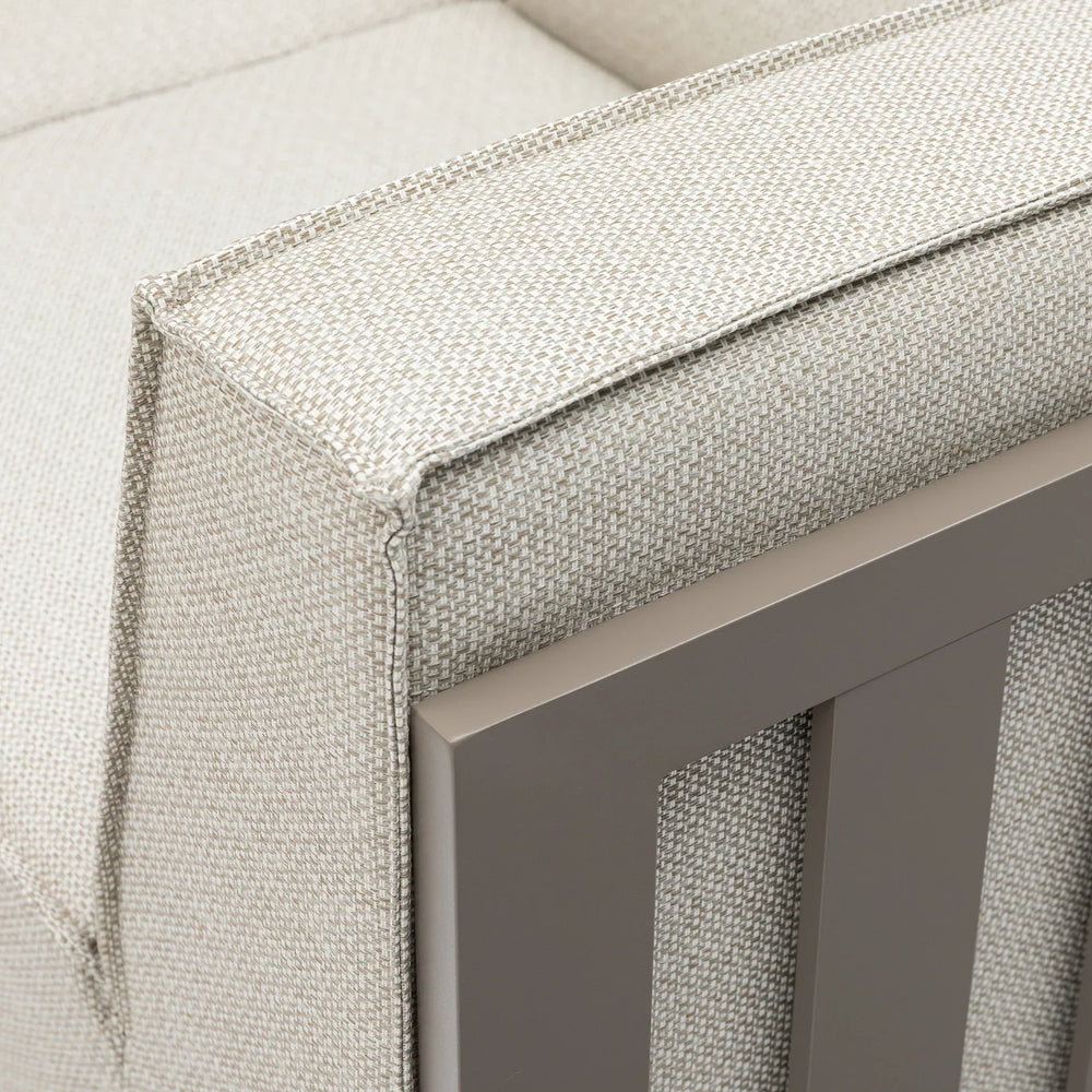Beige fabric sofa armrest with metal frame detail, close-up of upholstery texture