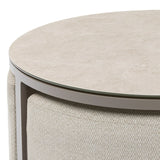 Round beige coffee table with glass top and textured fabric base, close-up detail view