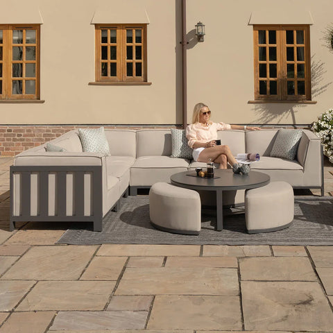 Modern outdoor corner sofa set in light grey with round coffee table on patio