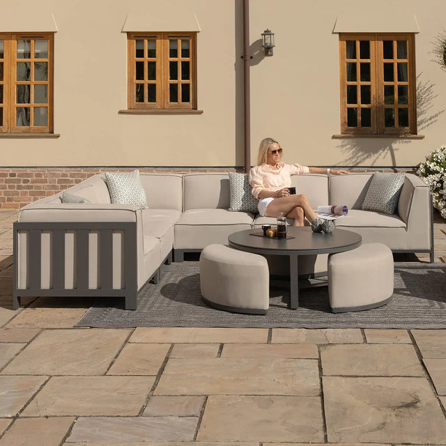 Modern outdoor corner sofa set in light grey with round coffee table on patio