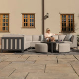 Modern outdoor corner sofa set with grey cushions and two round stools on patio
