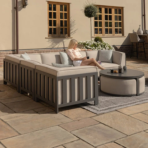 Modern outdoor corner sofa set with grey cushions and round coffee table on patio