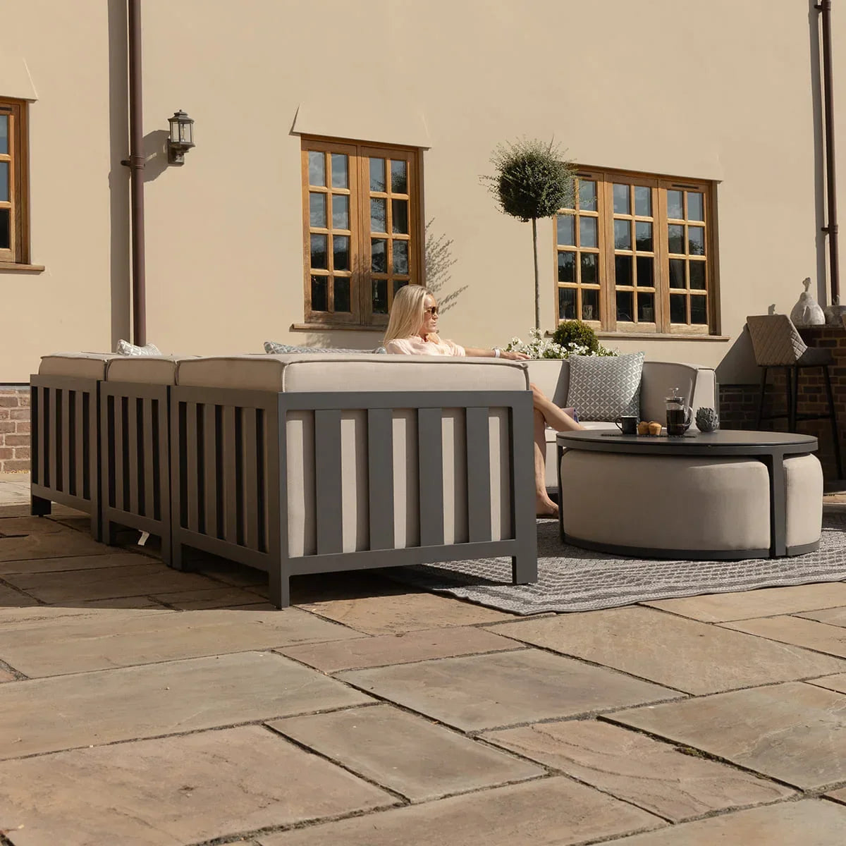 Grey outdoor sofa set with cushions and round coffee table on patio