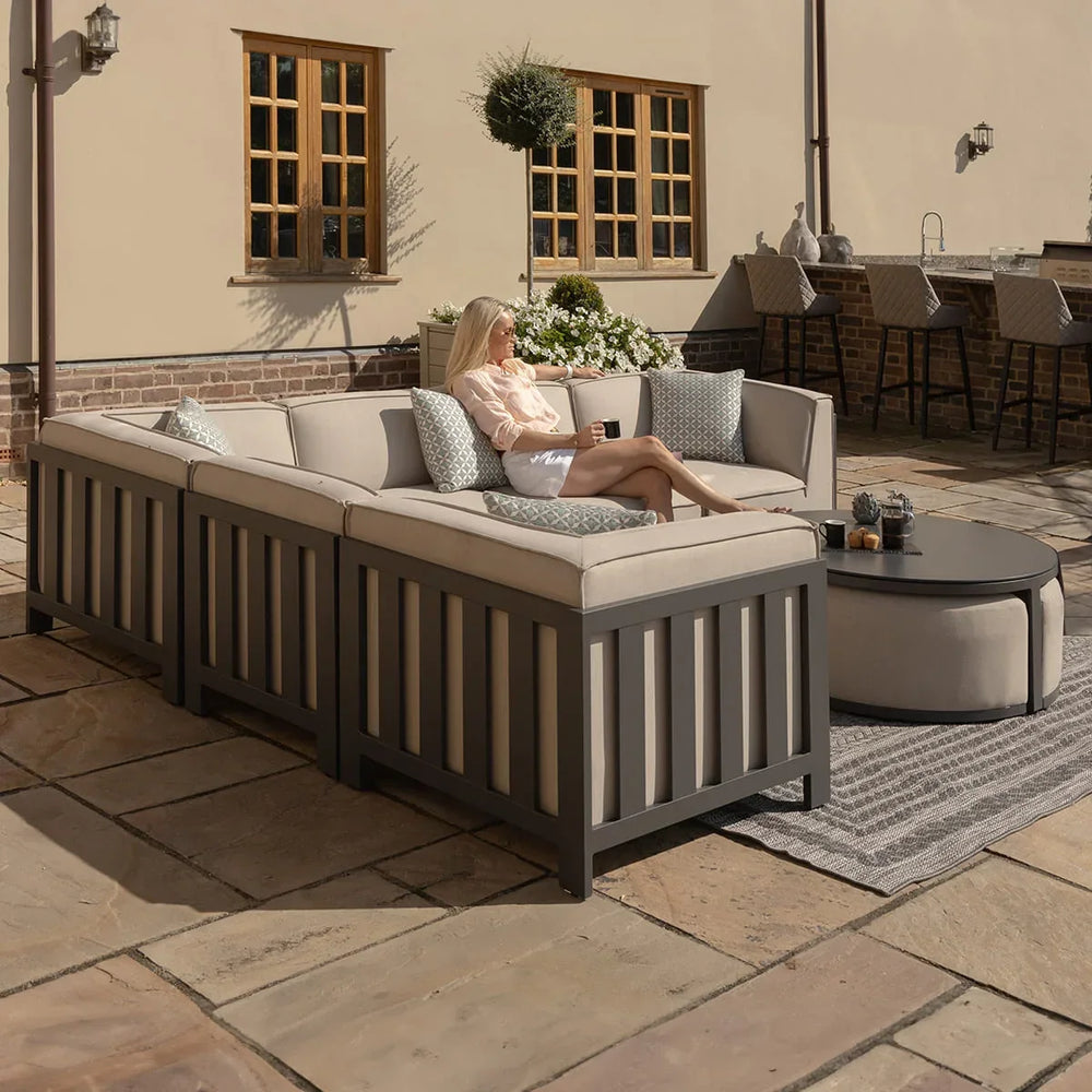 Outdoor corner sofa set with grey cushions and coffee table on a stone patio