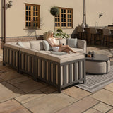 Outdoor corner sofa set with grey cushions and coffee table on a stone patio