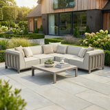 Beige outdoor corner sofa set with cushions and coffee table on stone patio