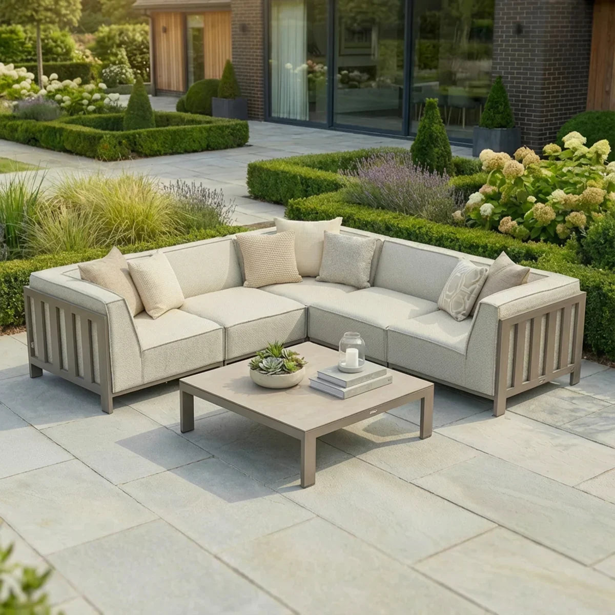 Beige outdoor corner sofa set with cushions and coffee table on stone patio in modern garden