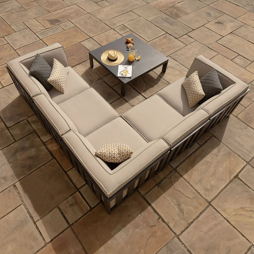 Beige outdoor corner sofa set with cushions and square coffee table on stone patio