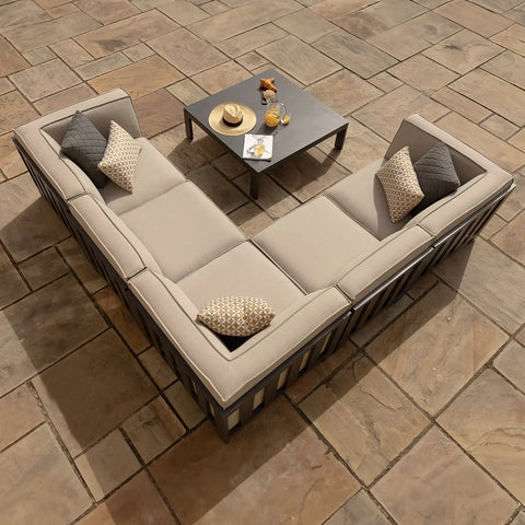 Beige outdoor corner sofa set with cushions and square coffee table on stone patio