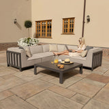 Grey outdoor corner sofa set with low coffee table on stone patio, cushions and snacks visible
