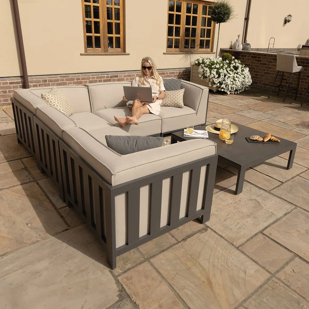 Outdoor corner sofa set with beige cushions and coffee table on stone patio
