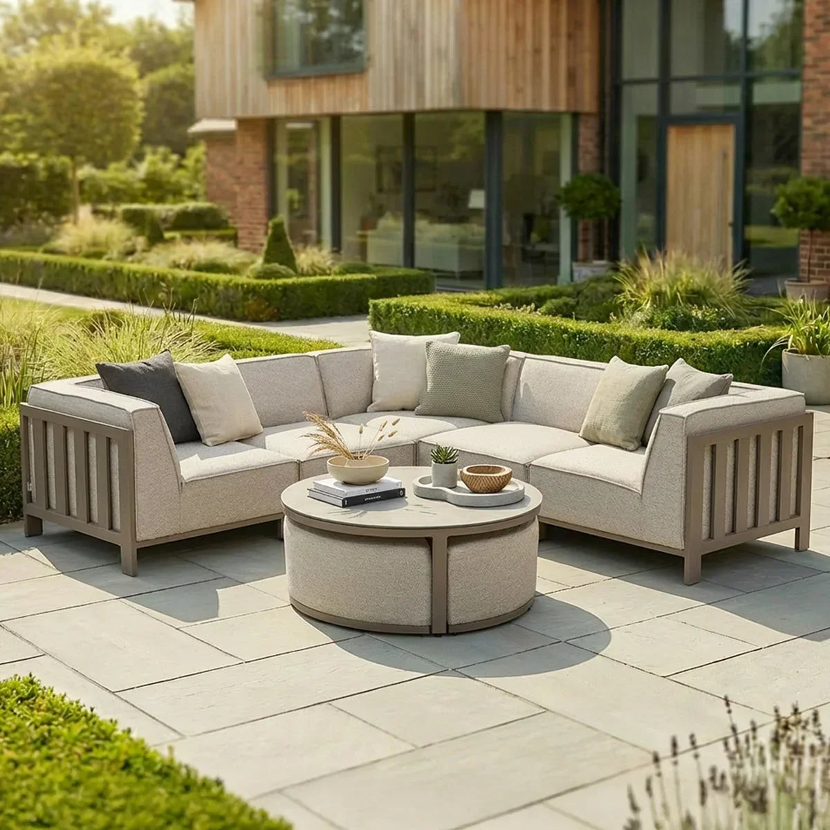 Beige outdoor corner sofa set with cushions and round coffee table on garden patio