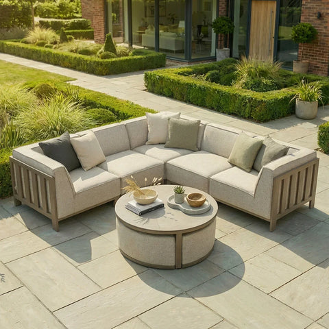 Beige outdoor corner sofa set with cushions and round coffee table on stone patio