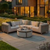 Outdoor corner sofa set with beige cushions and round coffee table on patio at sunset
