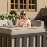 Outdoor corner sofa with light grey cushions and scatter pillows in a garden setting