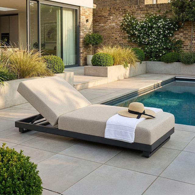 Beige outdoor sun lounger with adjustable backrest beside a pool on a modern patio