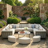 Outdoor garden sofa set with light cushions, round table, and ottomans on stone patio