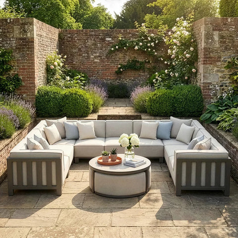Grey outdoor corner sofa set with cushions and round table on stone patio in garden